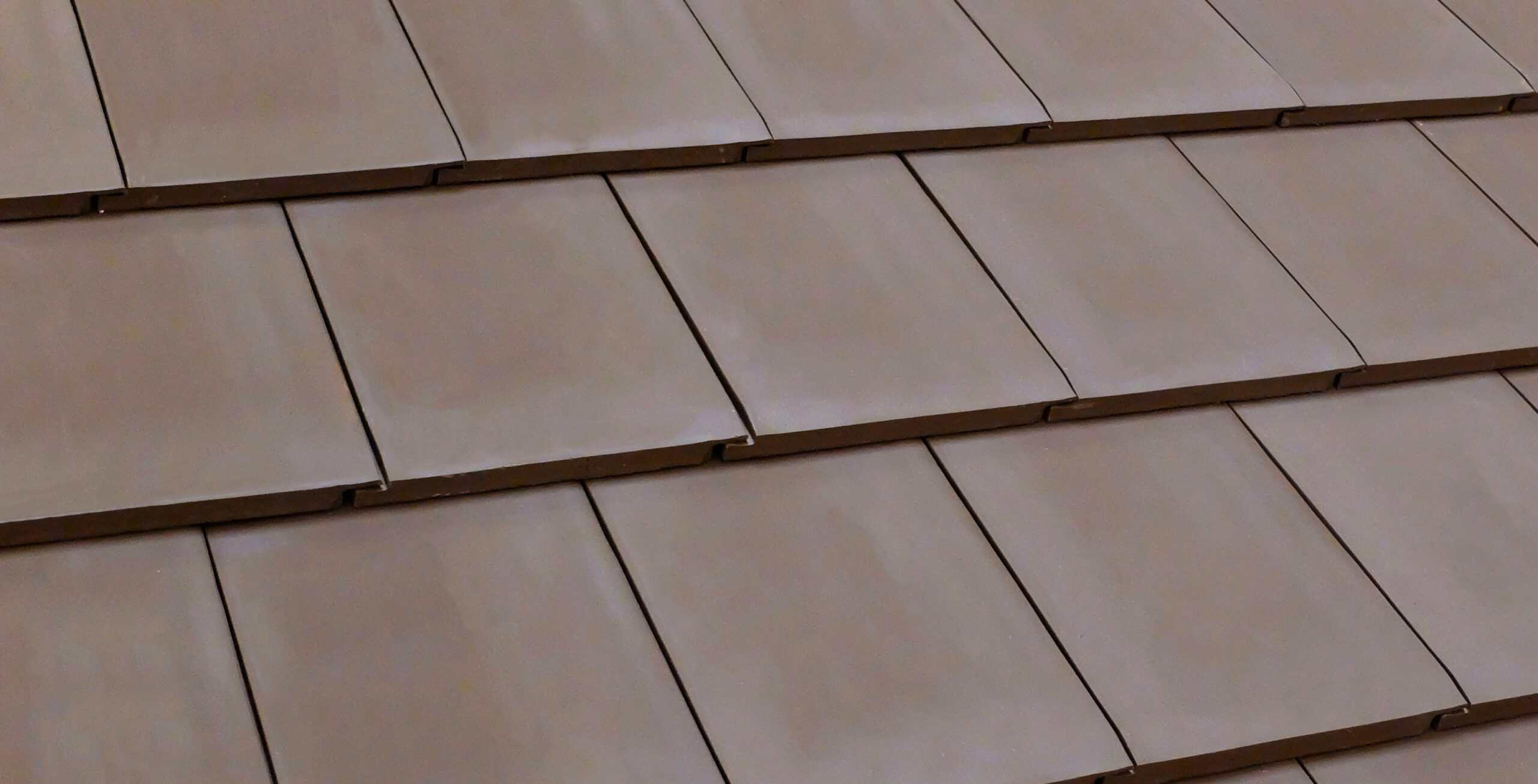Verea Flat Interlocking in Graphite - Close-up of tan flat clay roof tiles arranged in overlapping rows