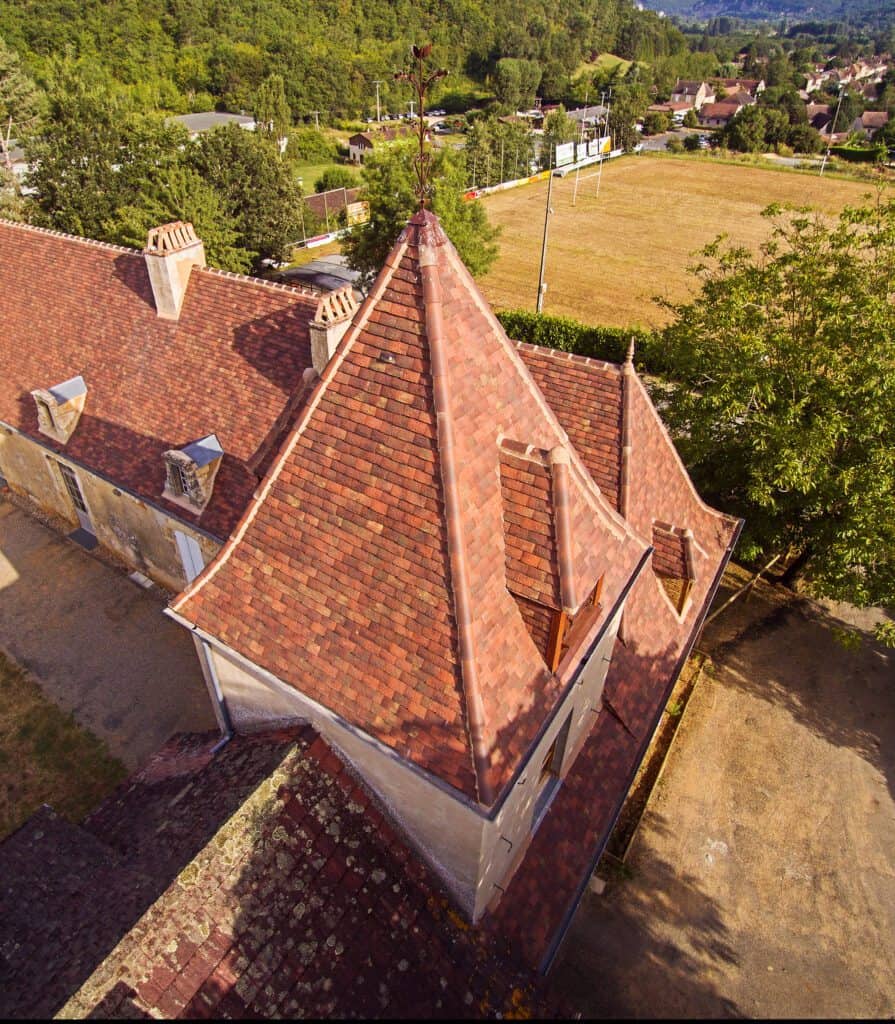 Close-up of French shingle roof tiles in Gabarre blend with mixed reds, browns, and moss hues, capturing natural variation and texture.