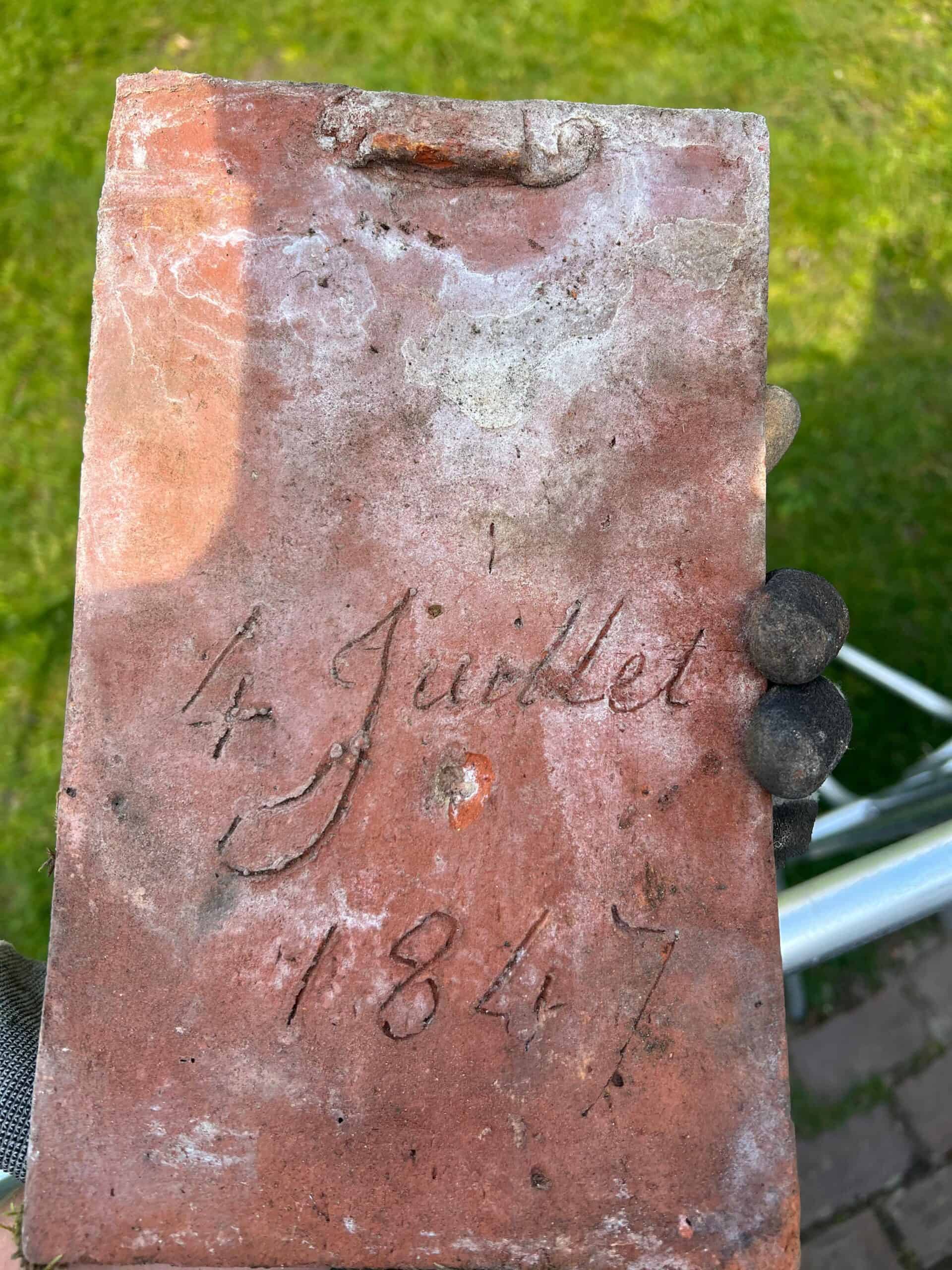 Original clay roof tile marked 1847 showing longevity of traditional roofing materials